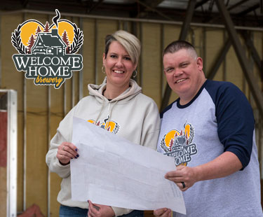 welcome home owners standing in front of build site