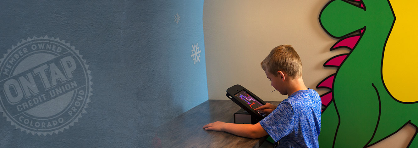 boy playing on tablet in brewster room at branch