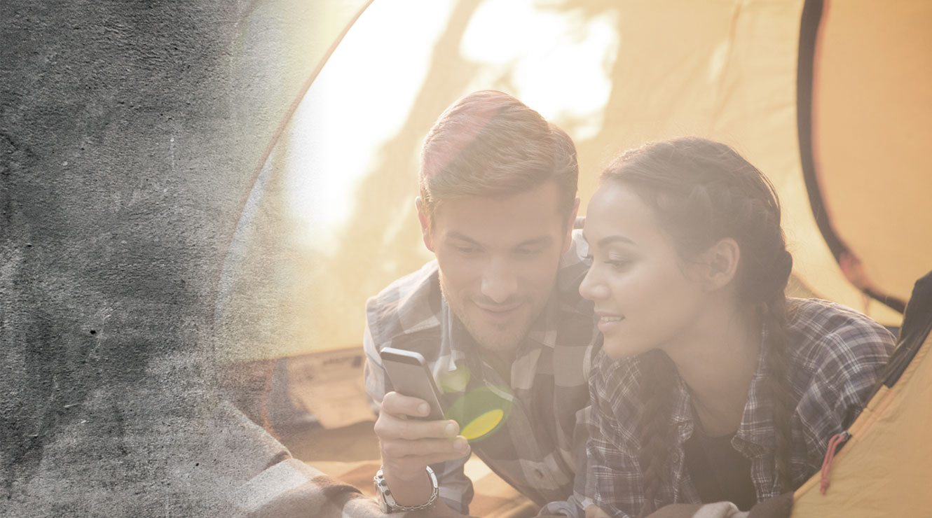 couple in tent looking at mobile device