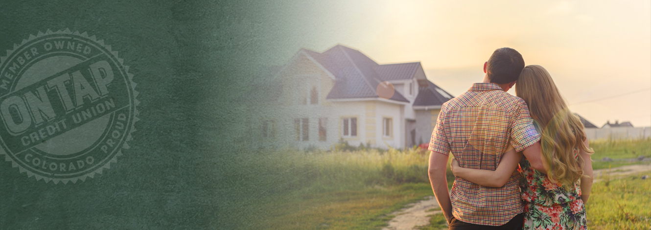 happy couple with arms around each other while looking at their house