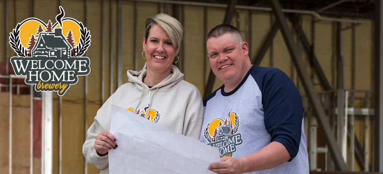 welcome home owners standing in front of build site